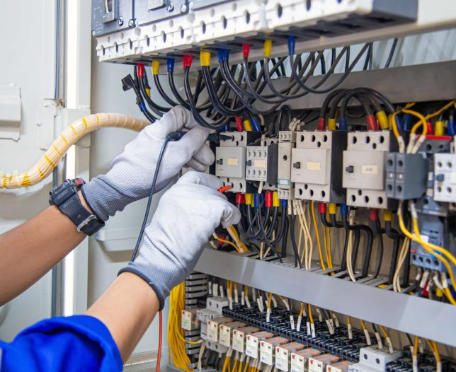 electricity-electrical-maintenance-service-engineer-hand-holding-ac-voltmeter-checking-electric-current-voltage-circuit-breaker-terminal-cable-wiring-main-power-distribution-board-min